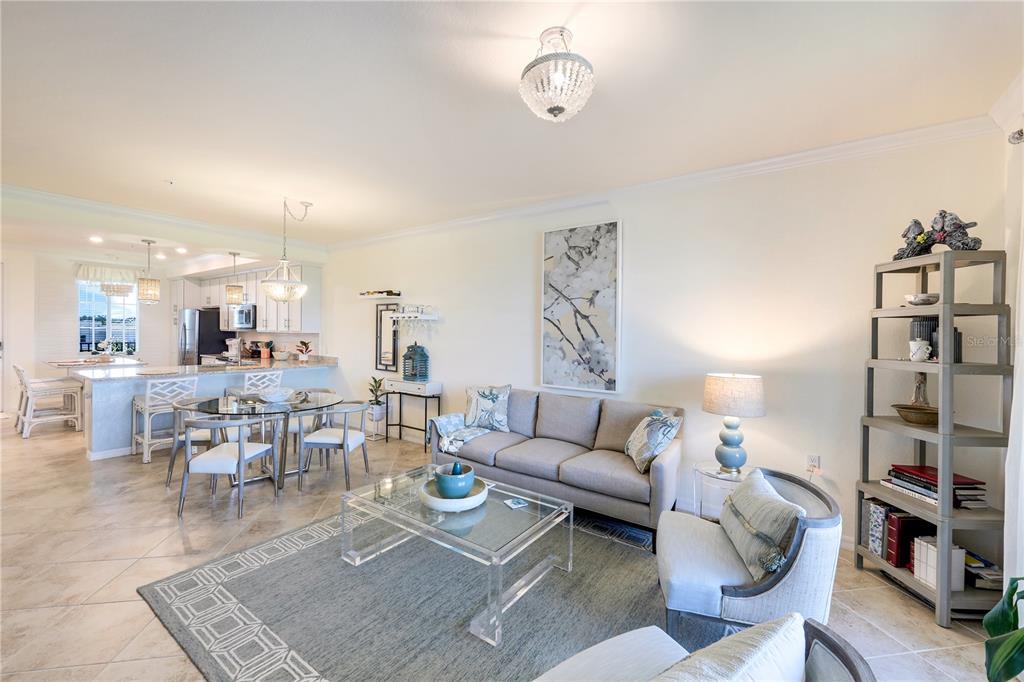 An open-concept living and dining area features tile floors, a gray sofa, and kitchen island — 14051 HERITAGE LANDING BOULEVARD UNIT 524, PUNTA GORDA, FL