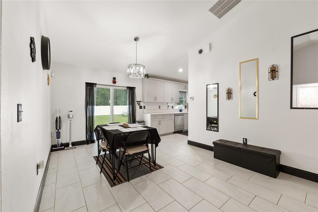 A dining area with tile floors, a chandelier, and a sliding glass door to the backyard — 3781 SE 144TH LANE, SUMMERFIELD, FL