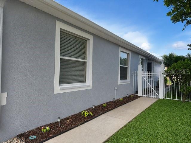 A side view of a gray stucco house with a concrete walkway and white fence — 21433 DIAMONTE DRIVE, LAND O LAKES, FL