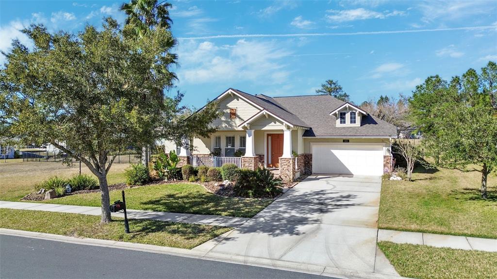 A single-story house with a tan exterior, stone accents, a front porch, and a garage — 19531 MOSSY OAK COURT, BROOKSVILLE, FL