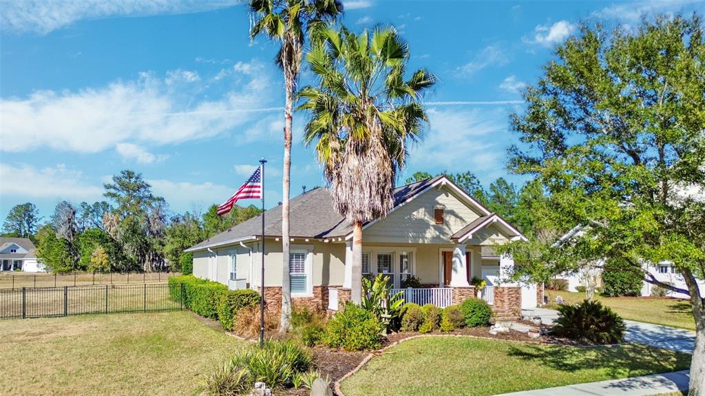 A single-story house with a palm tree, an American flag, and a fenced yard — 19531 MOSSY OAK COURT, BROOKSVILLE, FL