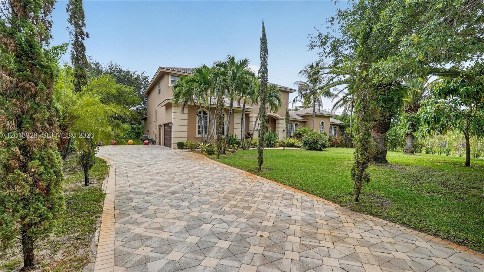 A two-story tan house with a paved driveway and palm trees in the front yard — 5960 NW 79th Way, Parkland FL 33067, PARKLAND, FL