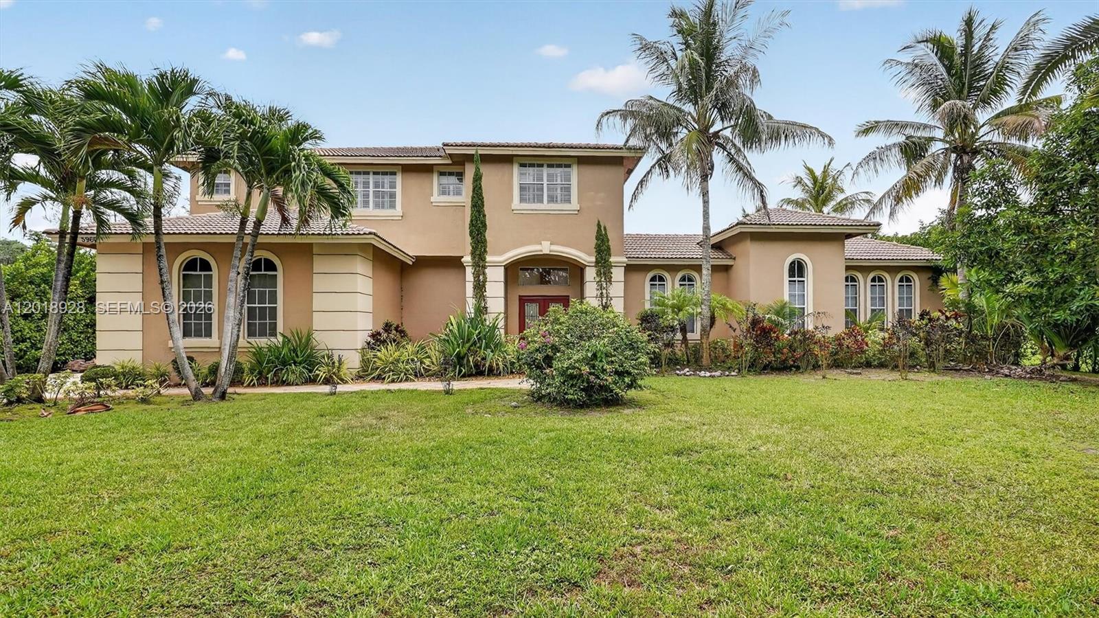 A two-story tan stucco house with arched windows and palm trees on a grassy lawn — 5960 NW 79th Way, Parkland FL 33067, PARKLAND, FL