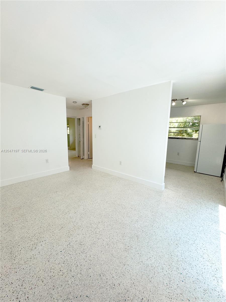 A bright, open-plan living area features white walls and light-colored speckled terrazzo flooring — MIAMI, FL