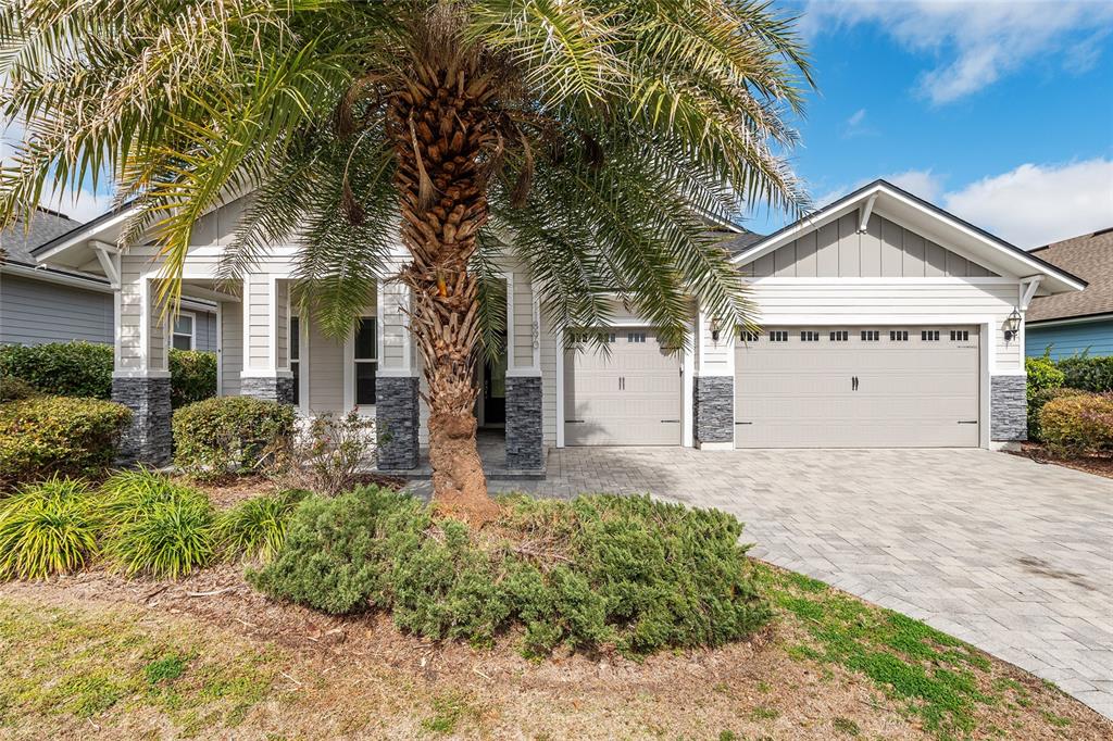 A single-story house with a palm tree, stone accents, and a paved driveway — 11890 SW 33RD LANE, GAINESVILLE, FL