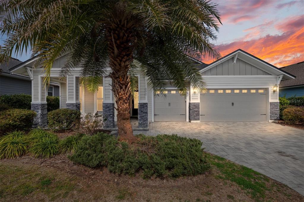 A single-story house with a gray exterior, stone accents, a palm tree, and a paved driveway — 11890 SW 33RD LANE, GAINESVILLE, FL