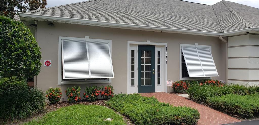 The exterior of a single-story building features a dark door, white shutters, and brick walkway — 16013 N FLORIDA AVENUE, LUTZ, FL