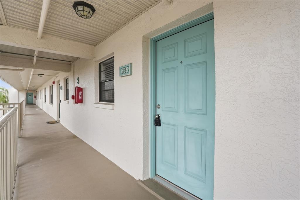 An exterior walkway features a light blue door marked 635 and a red fire extinguisher — 175 KINGS HIGHWAY UNIT 635, PUNTA GORDA, FL