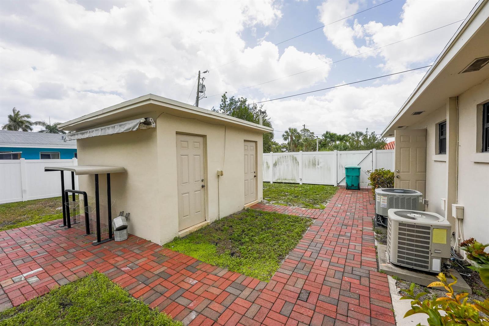 A backyard features a detached shed, brick walkways, and two air conditioning units near a house — 912 SE 4th Street, Boynton Beach FL 33435, BOYNTON BEACH, FL