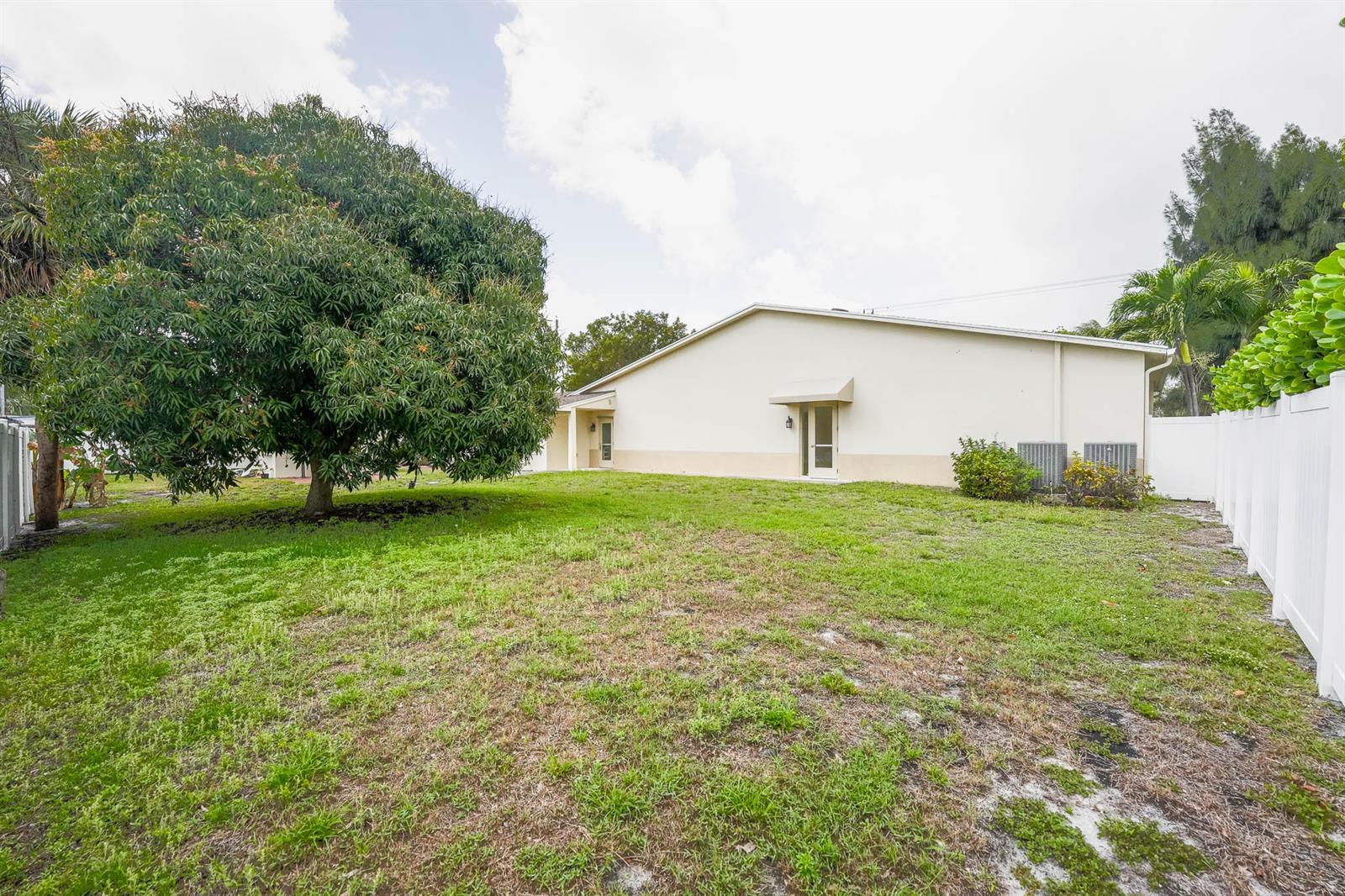A large tree stands in the backyard of a house with a white fence — 912 SE 4th Street, Boynton Beach FL 33435, BOYNTON BEACH, FL
