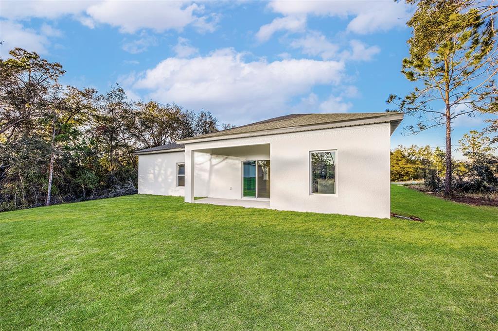 The exterior rear view of a white stucco house with a covered patio and lawn — 1342 CONGO COURT, POINCIANA, FL
