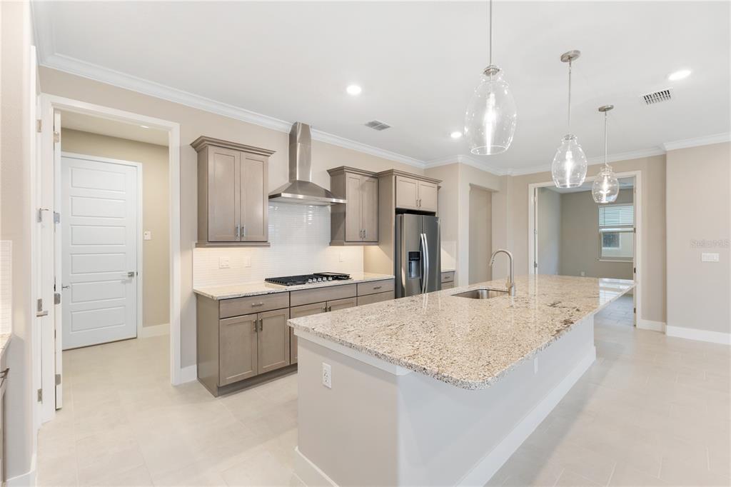 A kitchen features light gray cabinets, granite countertops, a large island, and stainless steel appliances — 4457 NW 53RD AVENUE, OCALA, FL