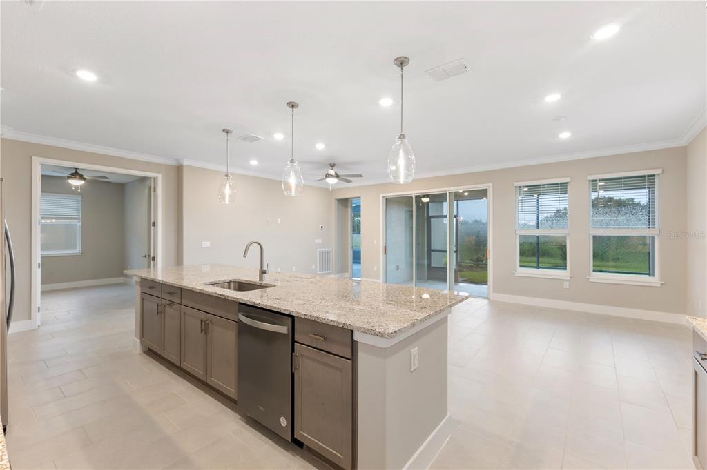 A kitchen island with granite countertops and stainless steel appliances sits in an open-concept room — 4457 NW 53RD AVENUE, OCALA, FL