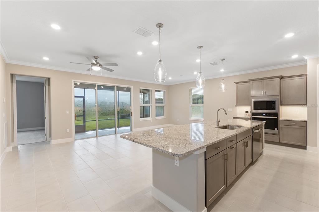 A kitchen with a granite island, gray cabinets, and sliding glass doors to a backyard — 4457 NW 53RD AVENUE, OCALA, FL