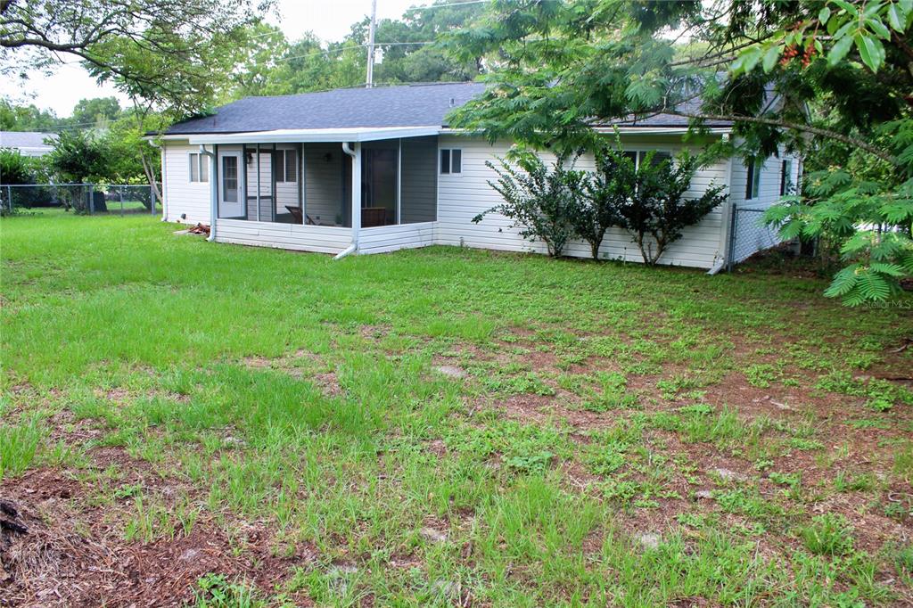 The exterior of a white, single-story house features a screened-in porch and a grassy yard — 10740 SW 62ND AVENUE ROAD, OCALA, FL