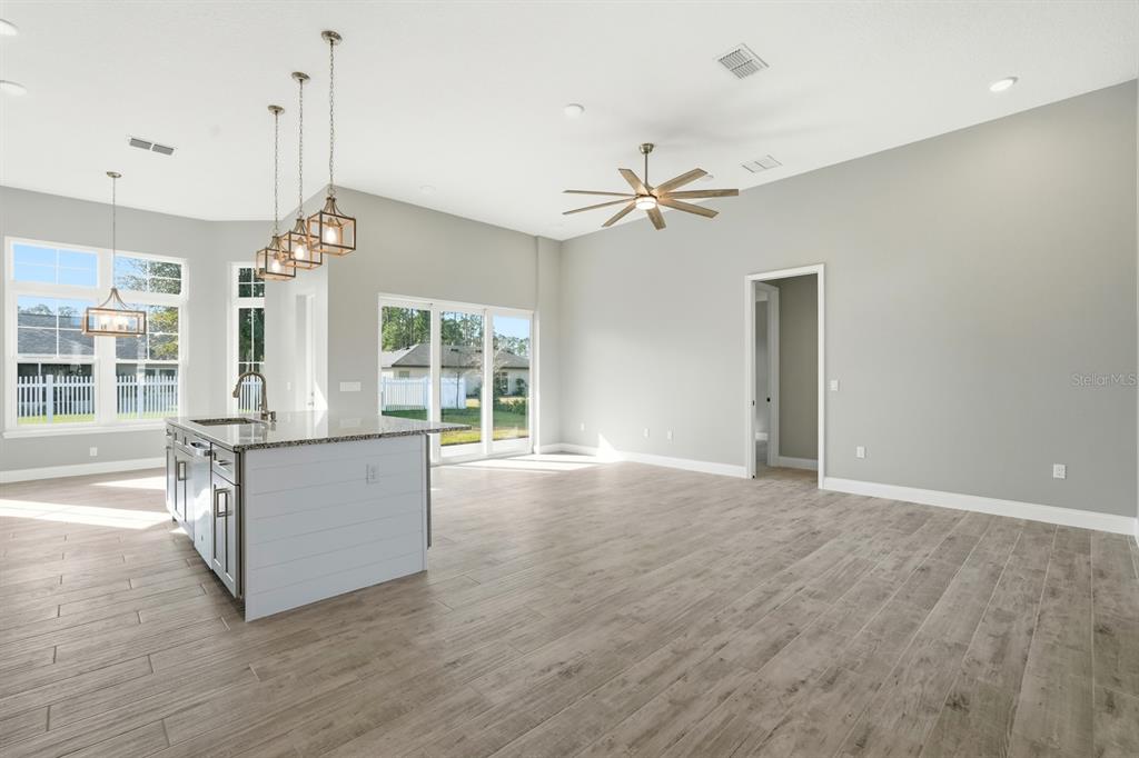 A kitchen island with pendant lights sits in an open-concept living area with wood-look flooring — 16 PIERCE LANE, PALM COAST, FL