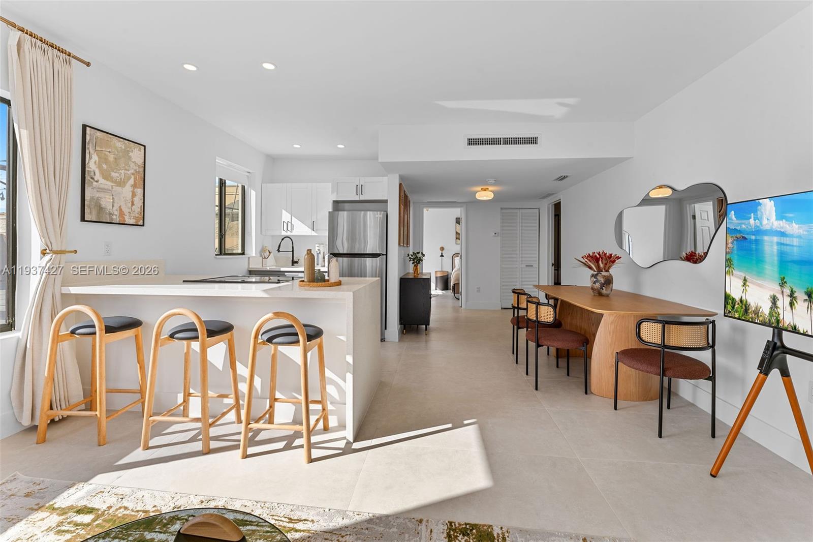 An open-concept kitchen and dining area features white cabinetry, a breakfast bar, and tile flooring — 1144 SW 4th St # 8, Miami FL 33130, MIAMI, FL