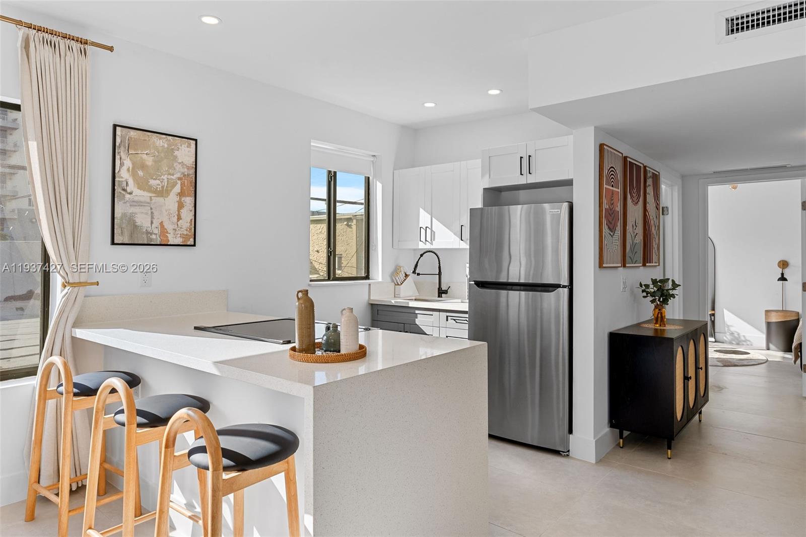 A modern kitchen features white cabinetry, stainless steel appliances, a quartz island, and bar seating — 1144 SW 4th St # 8, Miami FL 33130, MIAMI, FL