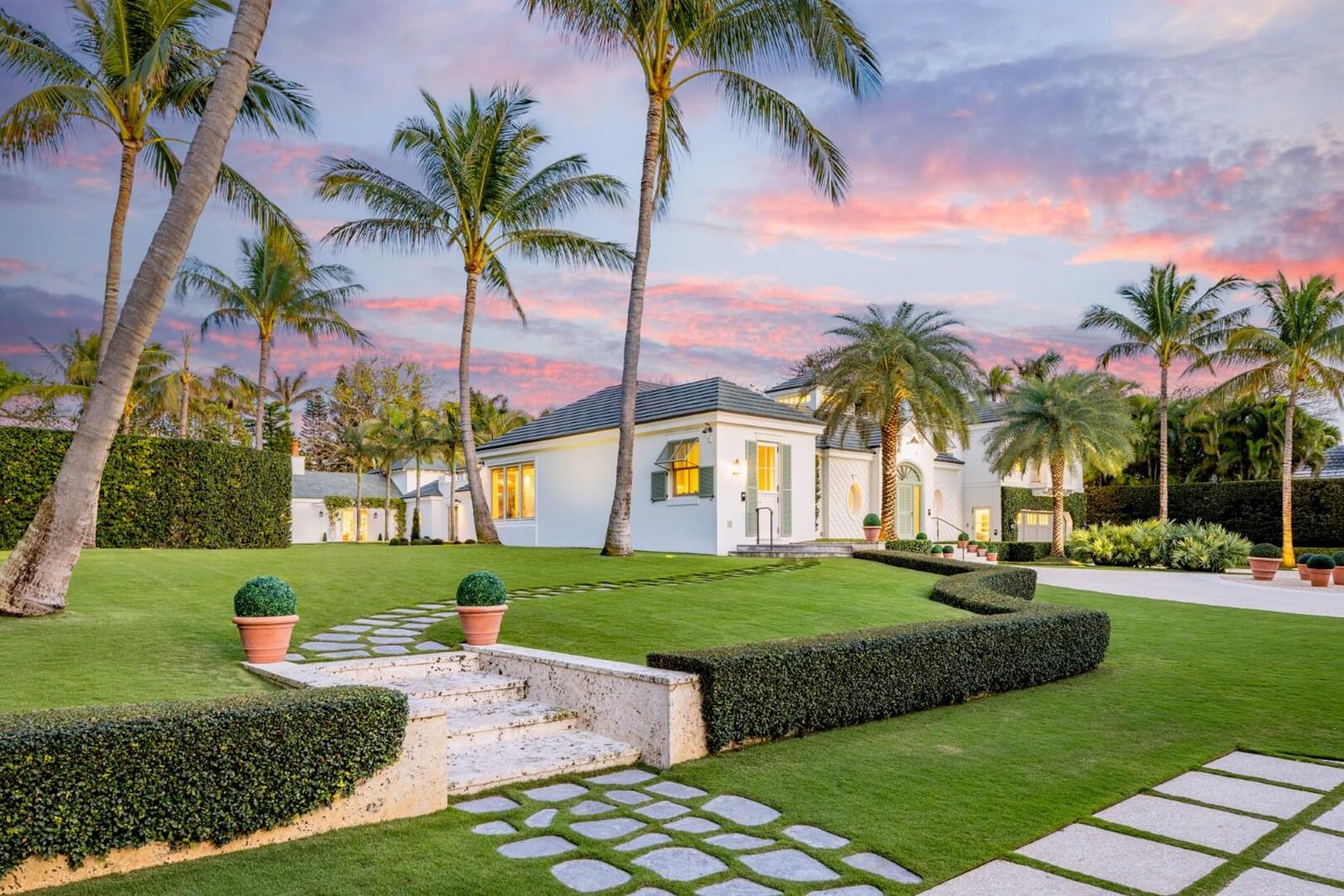 A white house with a manicured lawn, palm trees, and a stone walkway at sunset — 710 S County Road, Palm Beach FL 33480, PALM BEACH, FL