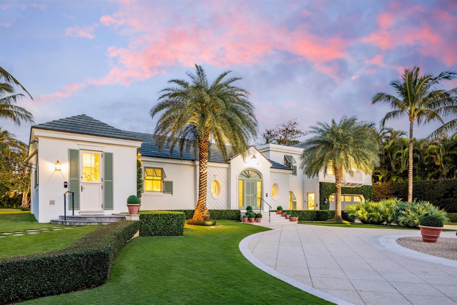 A white house with a circular driveway, palm trees, and green shutters under a sunset sky — 710 S County Road, Palm Beach FL 33480, PALM BEACH, FL