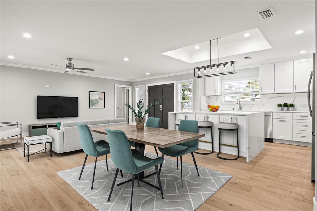 An open-concept living and dining area features a kitchen island, white cabinetry, and wood flooring — 170 98TH AVENUE N, ST PETERSBURG, FL