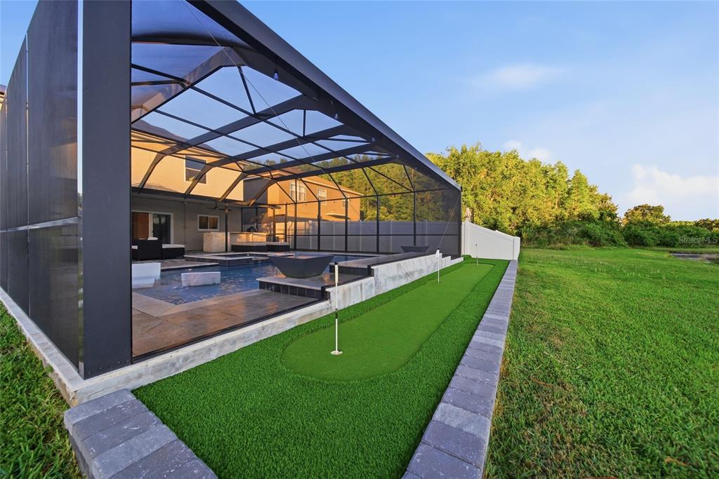 A backyard swimming pool with a screened enclosure and an adjacent artificial turf putting green — 18133 BAHAMA BAY DRIVE, TAMPA, FL