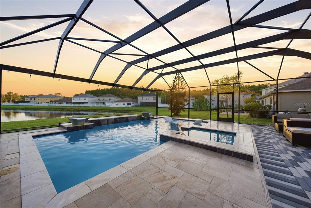 A screened-in swimming pool and spa overlook a pond at sunset — 18133 BAHAMA BAY DRIVE, TAMPA, FL