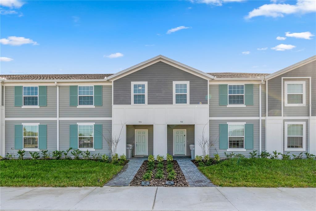 A two-story townhouse exterior with gray siding, teal shutters, and two front entry doors — 716 GARDENIA LANE, DAVENPORT, FL