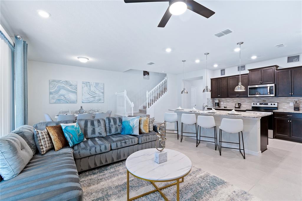An open-concept living room and kitchen featuring a grey sectional, marble coffee table, and island — 716 GARDENIA LANE, DAVENPORT, FL