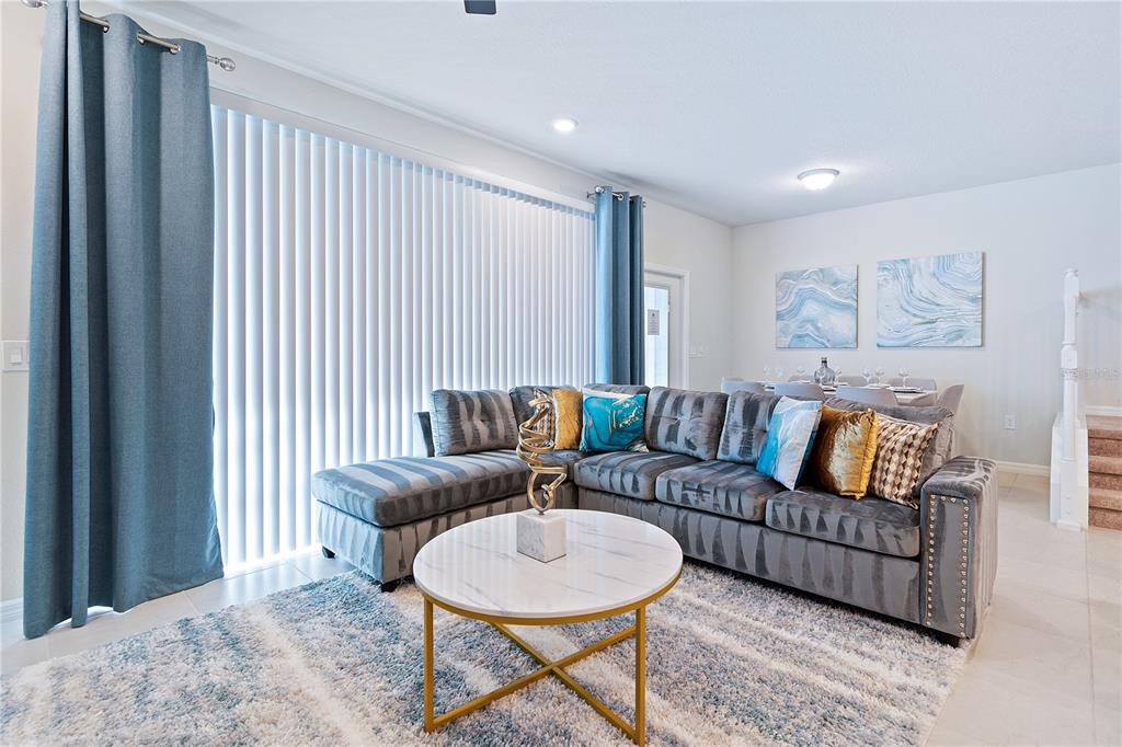 A living room features a grey sectional sofa, a marble coffee table, and blue curtains — 716 GARDENIA LANE, DAVENPORT, FL