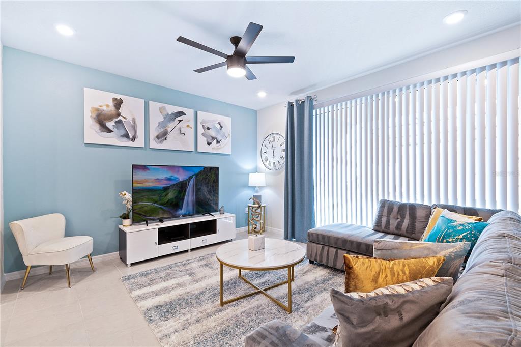 A living room features a blue accent wall, a sectional sofa, and a television console — 716 GARDENIA LANE, DAVENPORT, FL
