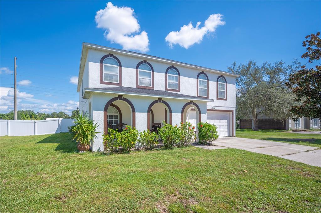 A two-story house with a white stucco exterior, arched windows, and a front porch — 5155 SPANISH OAKS DRIVE, LAKELAND, FL