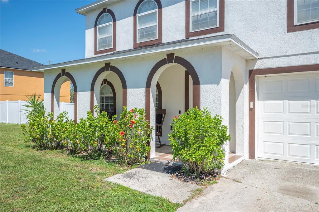 A two-story house exterior features a white stucco facade, arched entryway, and a front garden — 5155 SPANISH OAKS DRIVE, LAKELAND, FL