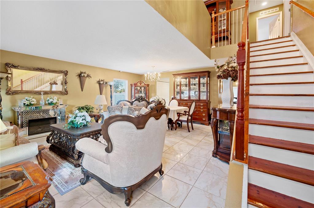A living room with tile floors, a staircase, and traditional furniture under a high ceiling — 5155 SPANISH OAKS DRIVE, LAKELAND, FL