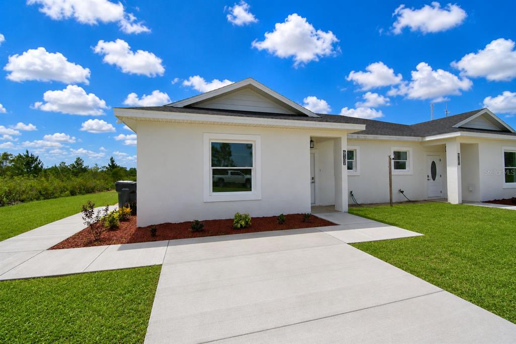 A white, single-story duplex with a concrete driveway and a grassy front yard — 7951 SARASOTA DRIVE UNIT A, INDIAN LAKE ESTATES, FL
