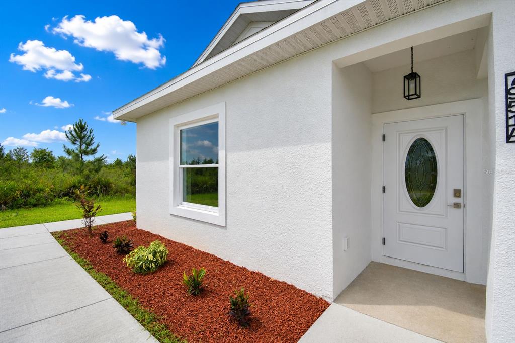 A white stucco house exterior features a front door with an oval glass insert — 7951 SARASOTA DRIVE UNIT A, INDIAN LAKE ESTATES, FL