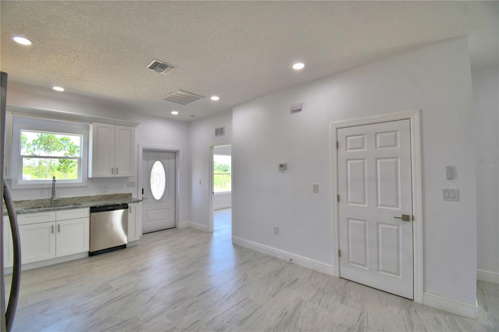 A kitchen area features white cabinets, stainless steel appliances, and light-colored tile flooring — 7951 SARASOTA DRIVE UNIT A, INDIAN LAKE ESTATES, FL