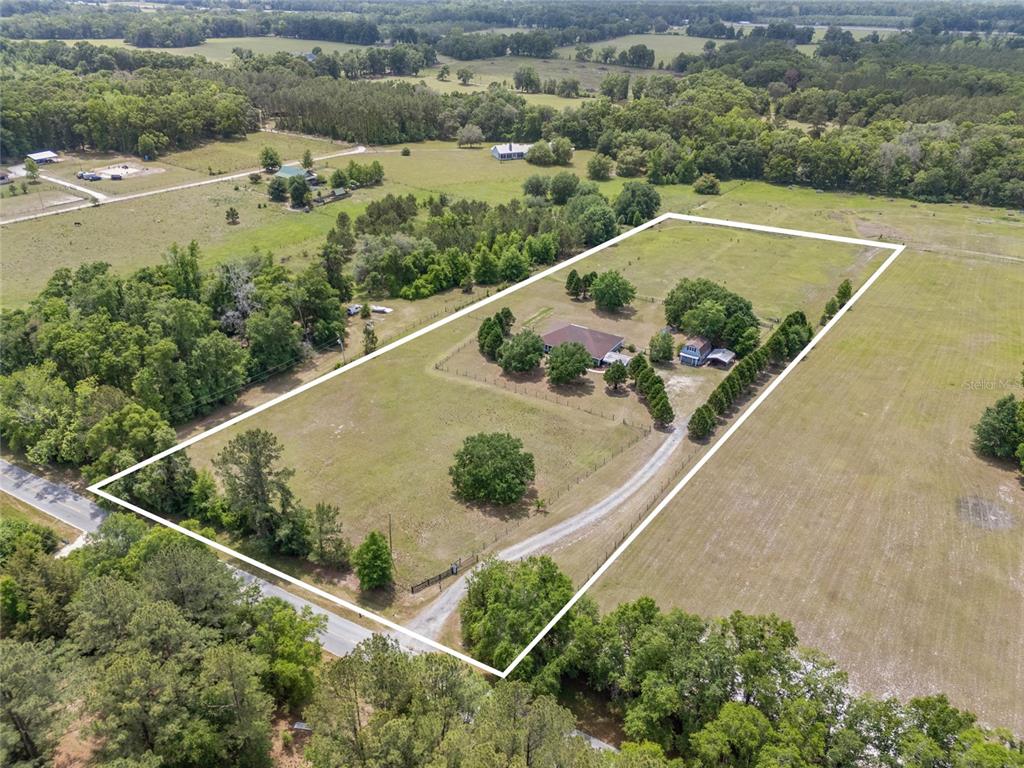 An aerial view shows a house and outbuilding situated on a large, fenced rural lot — 29104 N COUNTY ROAD 1491, ALACHUA, FL