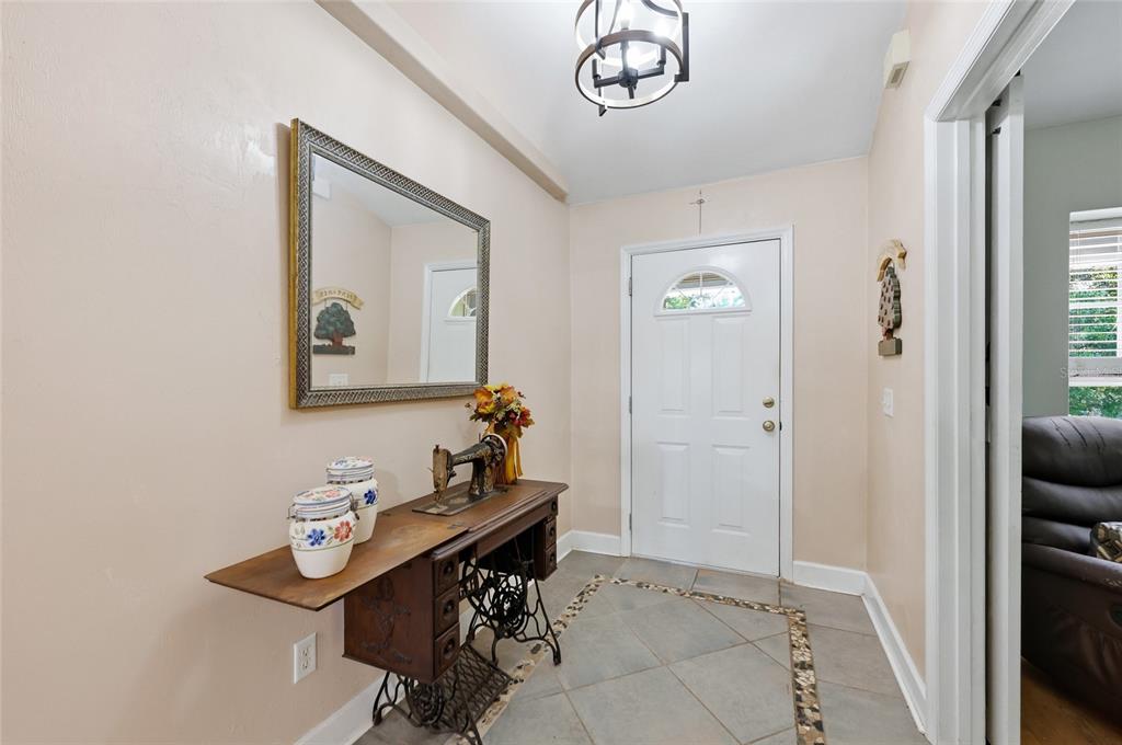 An entryway features a tiled floor, a vintage sewing machine table, and a wall mirror — 29104 N COUNTY ROAD 1491, ALACHUA, FL