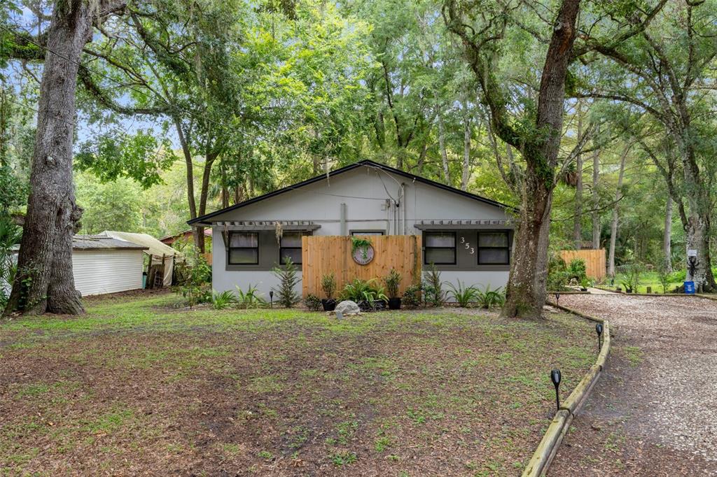 A single-story house with a wooden privacy screen stands in a wooded, grassy yard — 353 N ROBIN HOOD ROAD, INVERNESS, FL