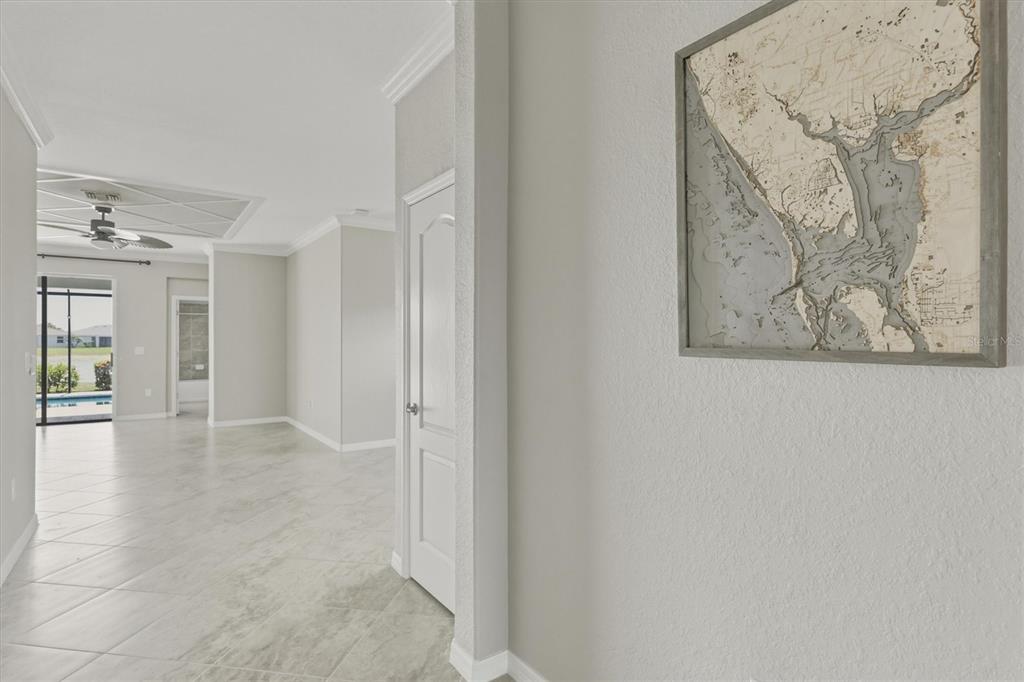 An entryway features a gray glass-paneled door, a wooden console table, and wall-mounted fish decor — 15113 SPANISH POINT DRIVE, PORT CHARLOTTE, FL