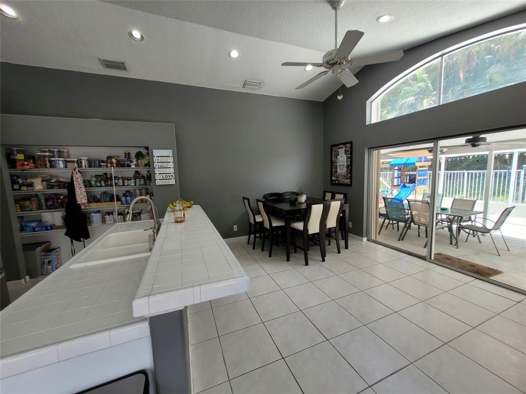 A kitchen with white tile counters and an open dining area featuring sliding glass doors — 6416 BARTON CREEK Circle, Lake Worth FL 33463, LAKE WORTH, FL