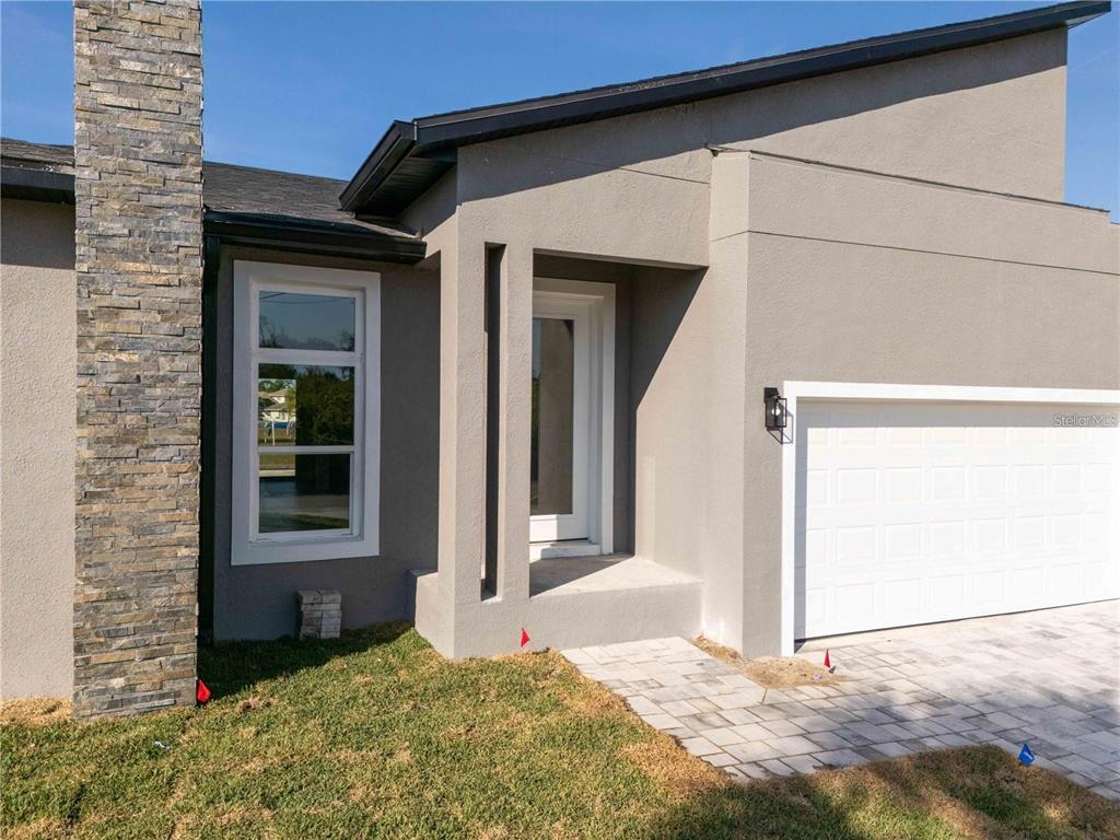 A modern house exterior features a stone chimney, gray stucco walls, and a white garage — 15 RAMBLEWOOD STREET, PORT CHARLOTTE, FL