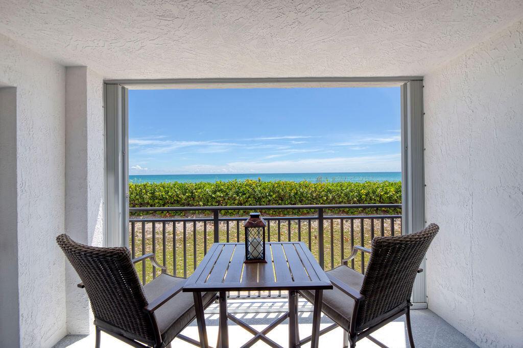 A balcony with a table and two chairs overlooks a beach and the ocean — 10102 S Ocean Drive # 204a, Jensen Beach FL 34957, JENSEN BEACH, FL