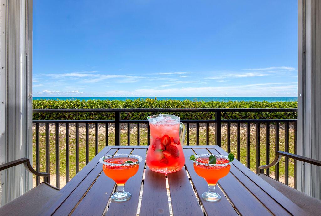A wooden table with a pitcher and two cocktails sits on a balcony overlooking the ocean — 10102 S Ocean Drive # 204a, Jensen Beach FL 34957, JENSEN BEACH, FL