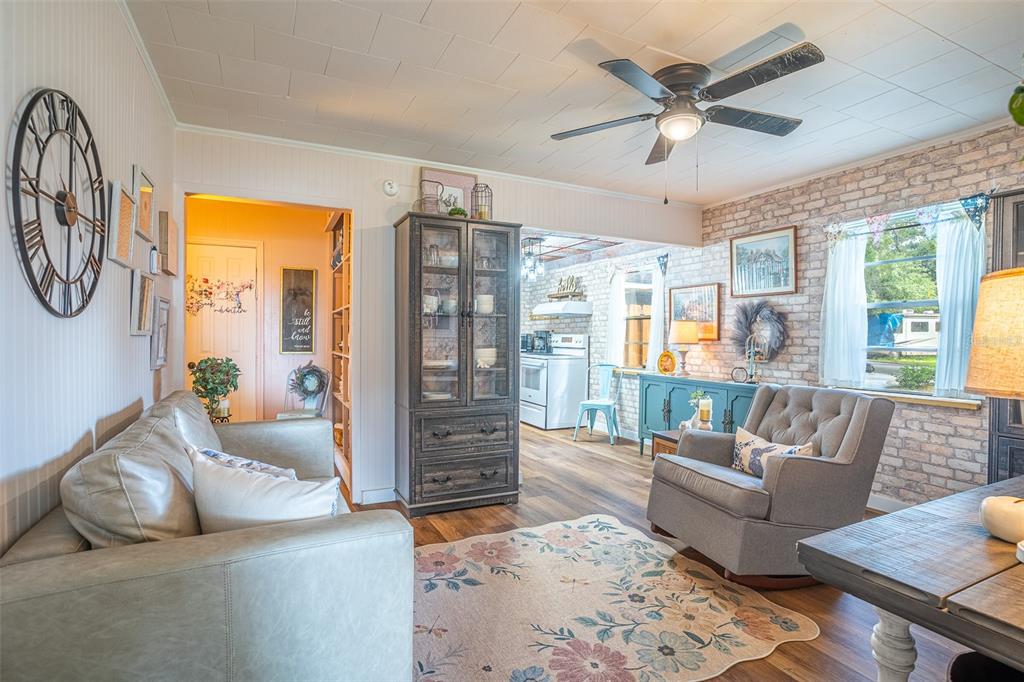 A living room features a grey sofa, a rocking chair, a hutch, and a brick wall — 310 RICO WAY, AUBURNDALE, FL