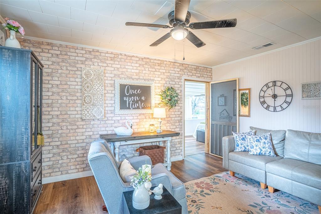 A living room features a faux brick wall, a gray sofa, and a ceiling fan — 310 RICO WAY, AUBURNDALE, FL