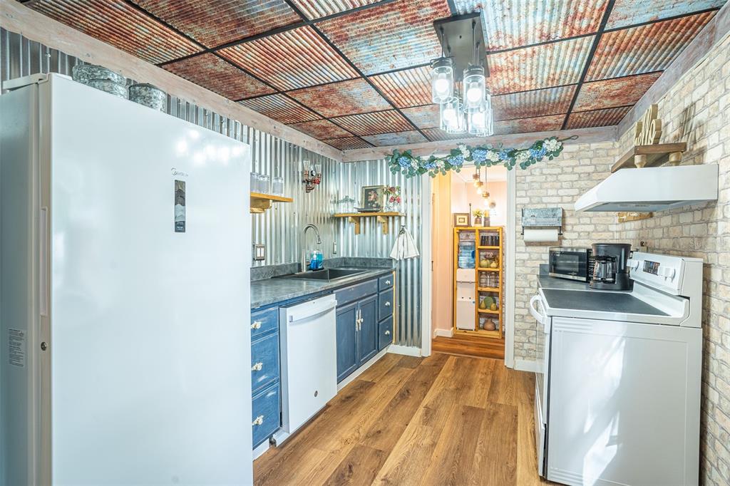 A rustic kitchen features corrugated metal walls, a rusted metal ceiling, and blue cabinets — 310 RICO WAY, AUBURNDALE, FL