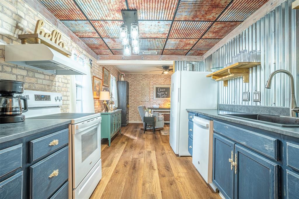A rustic kitchen features corrugated metal walls, a rusted metal ceiling, and blue cabinets — 310 RICO WAY, AUBURNDALE, FL
