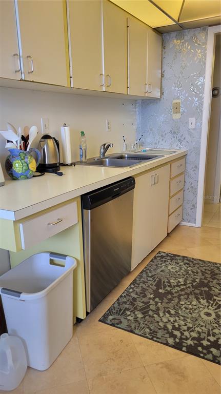 A kitchen features light-colored cabinets, a stainless steel dishwasher, a sink, and patterned wallpaper — 1000 LONGBOAT CLUB ROAD UNIT 406, LONGBOAT KEY, FL